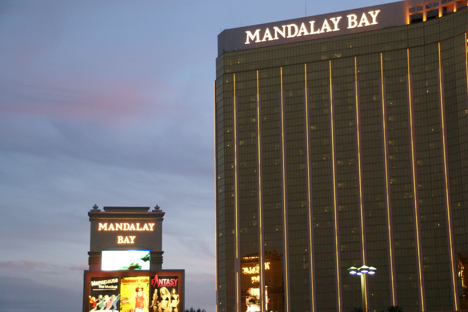 Golden Mandalay Bay hotel tower and roadside sign at dusk in Las Vegas